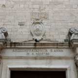 La porta d'accesso � racchiusa da un architrave originario, al di sopra del quale si erge un teschio, simbolo dell'arciconfraternita di San Marco della Buona Morte. Un�epigrafe invece ricorda quando la chiesa fu gestita dai nobili lombardi giunti a Bari al seguito di Iabella d�Aragona e Bona Sforza, assumendo il nome di Sant�Ambrogio prima e Sant'Agostino poi, con il subentro dei monaci devoti all'Ipponate